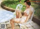 A naked woman sitting on a white chair next to a table.