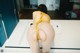 A woman in a yellow bikini is tied up to a table.