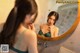 A woman in a green dress looking at herself in the mirror.