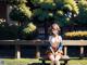 A woman sitting on a bench in a park.